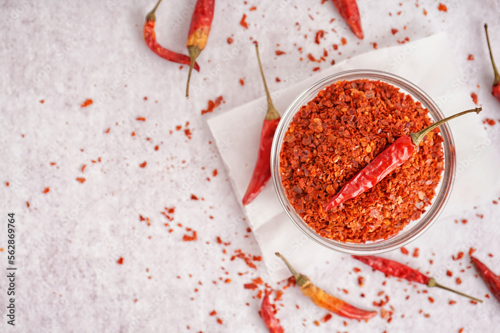 Bowl of chipotle chili flakes and dried jalapeno peppers on light background