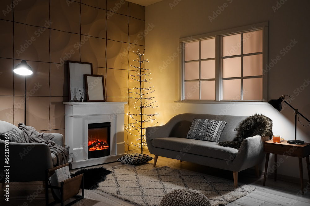 Interior of modern living room with electric fireplace, glowing lamps and sofa