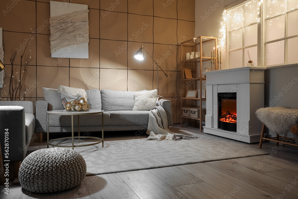 Interior of modern living room with electric fireplace, window and glowing lights