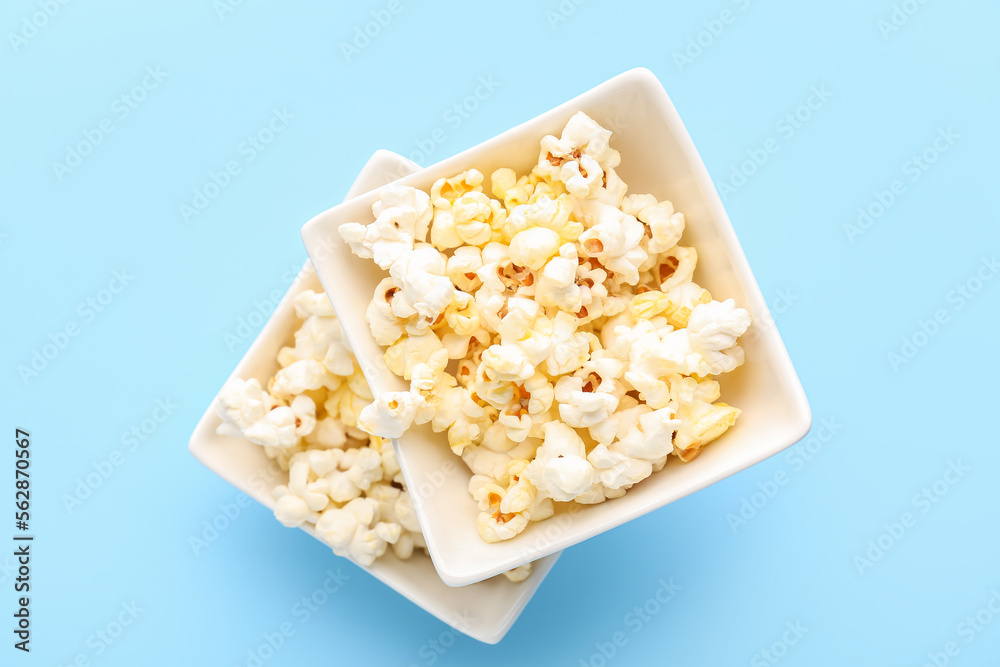 Ceramic bowls with tasty popcorn on color background