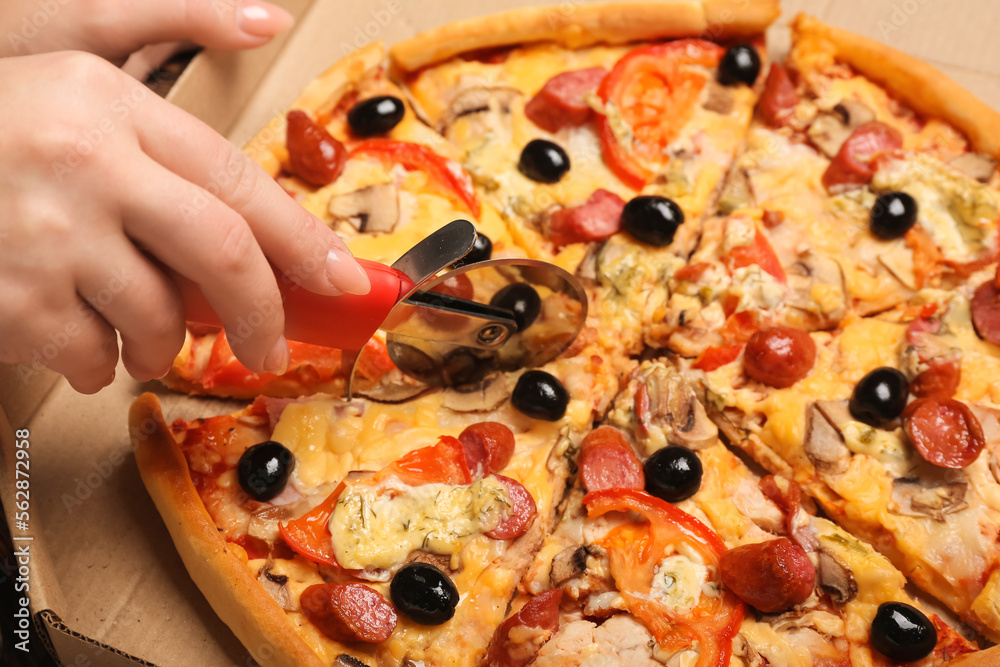 Woman cutting tasty pizza, closeup