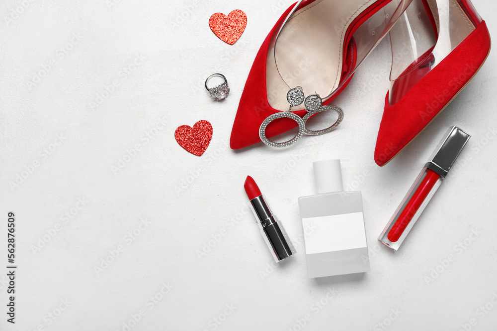 Perfume with cosmetic products, jewelry, heels and hearts for Valentines day on white background