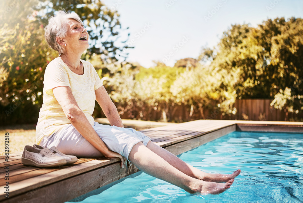 Elderly woman with her feet in the water of the pool while on a vacation, adventure or outdoor trip 