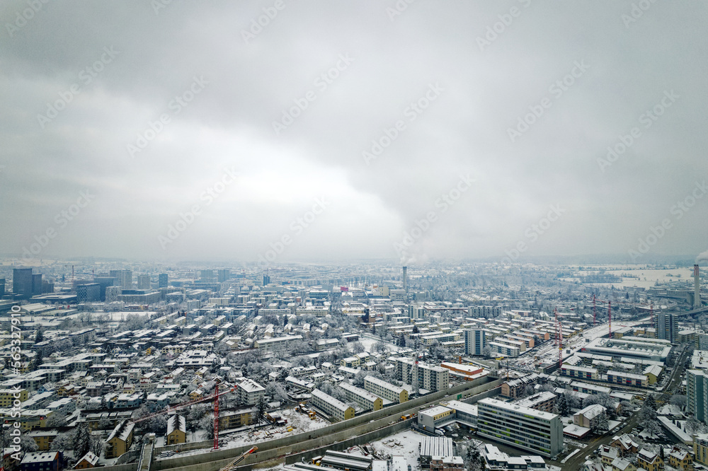 Aerial view over snow covered City of Zürich with skyline and gray cloudy winter sky on a snowy late