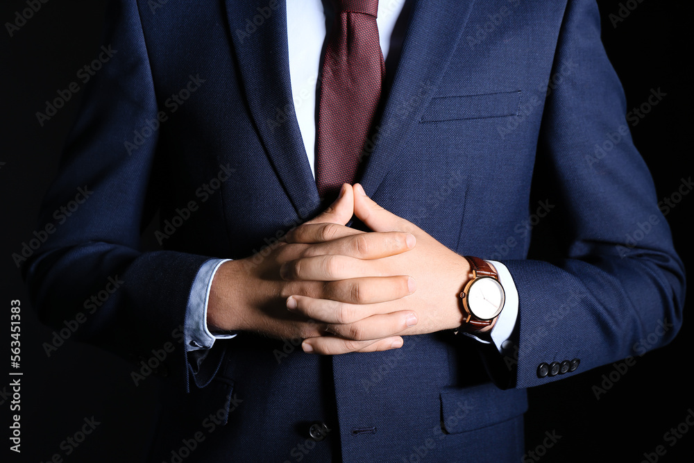 Young businessman in suit on black background, closeup