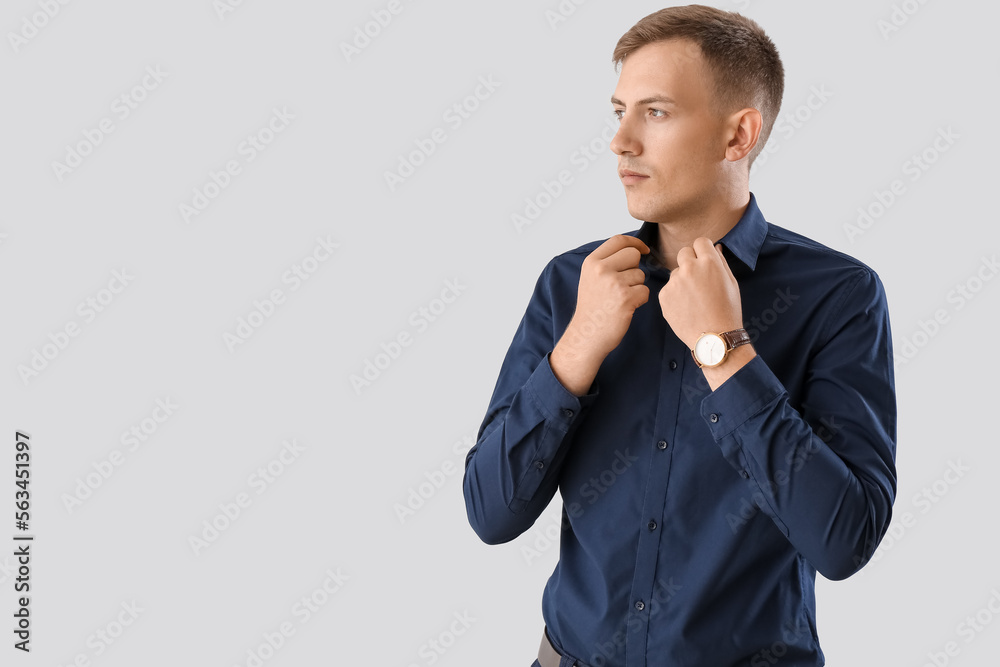 Young businessman in blue shirt on light background