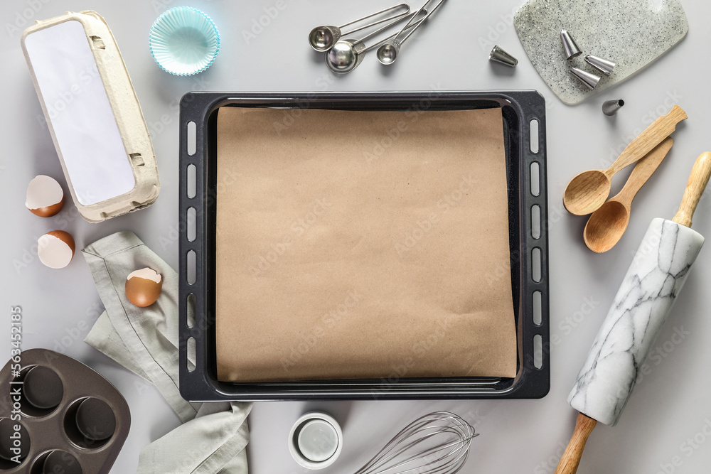 Baking trays with utensils on light background