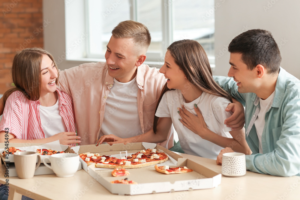 Group of friends with pizza spending time together at table in kitchen