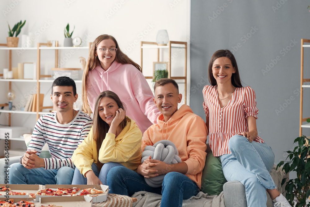 Group of friends with pizza spending time together in living room