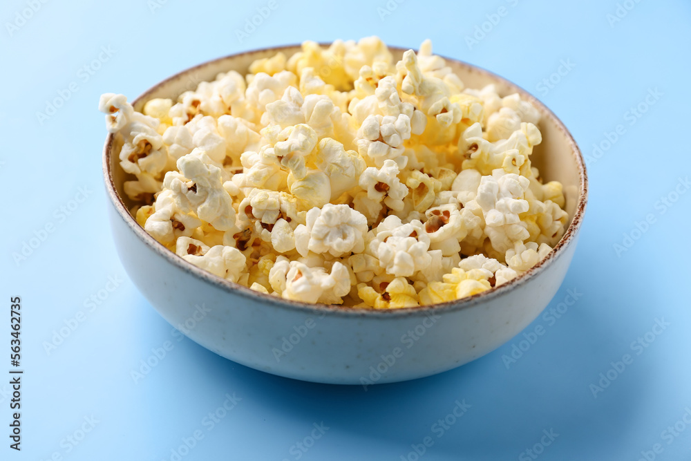 Bowl full of tasty popcorn on color background