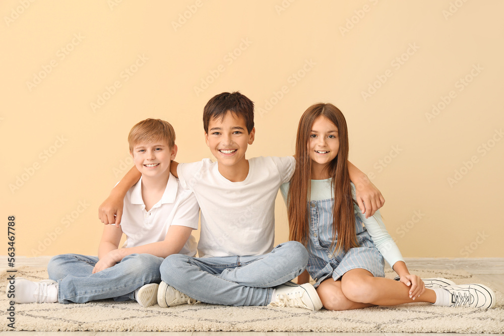 Little friends sitting near beige wall