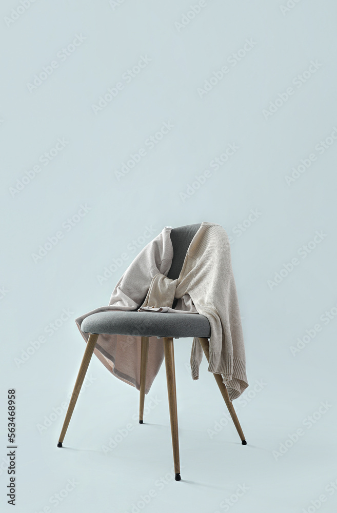 Chair with sweaters on grey background