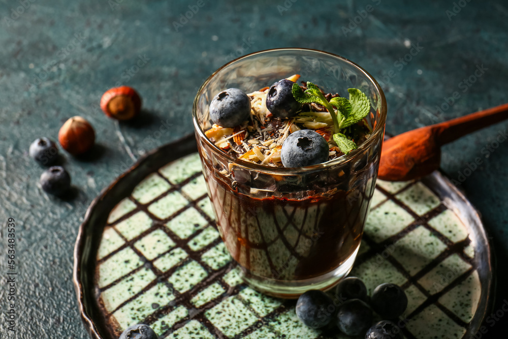 Plate with glass of delicious chocolate pudding, blueberry and almond on black table