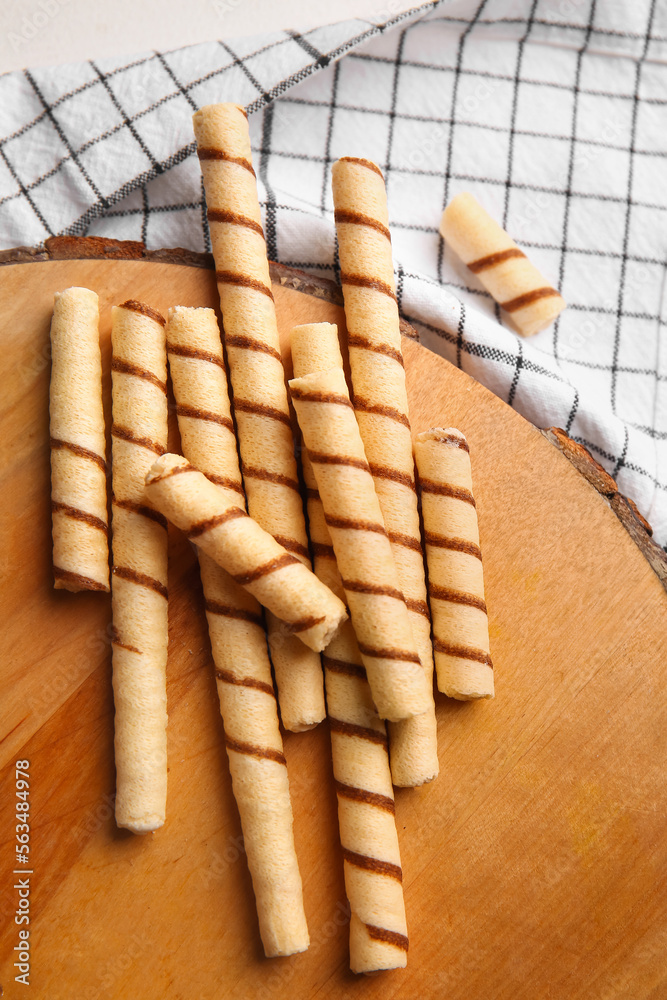 Cutting board with tasty wafer rolls and kitchen towel on table