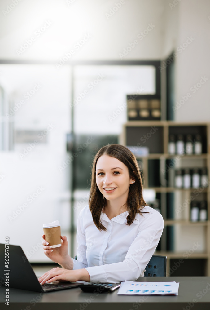 Young beautiful woman typing on tablet and laptop while sitting at the working wooden table modern o