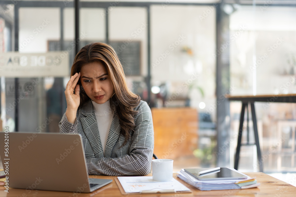 Asian business woman feeling stress at work when faced with difficult and hard work Feeling headache