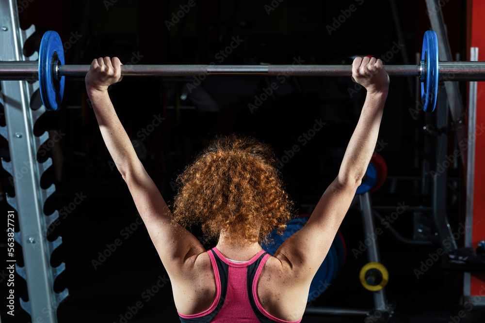 Woman bodybuilder engaged with a barbell in the gym