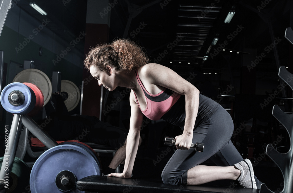 attractive young woman engaged with dumbbells in the gym.