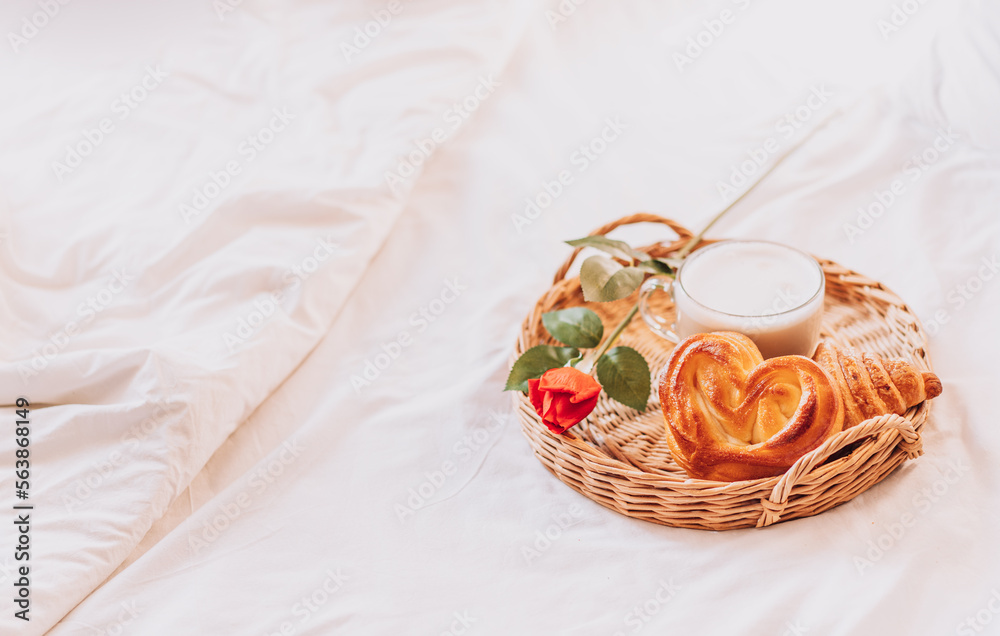 Tray with croissants on white bed linen.