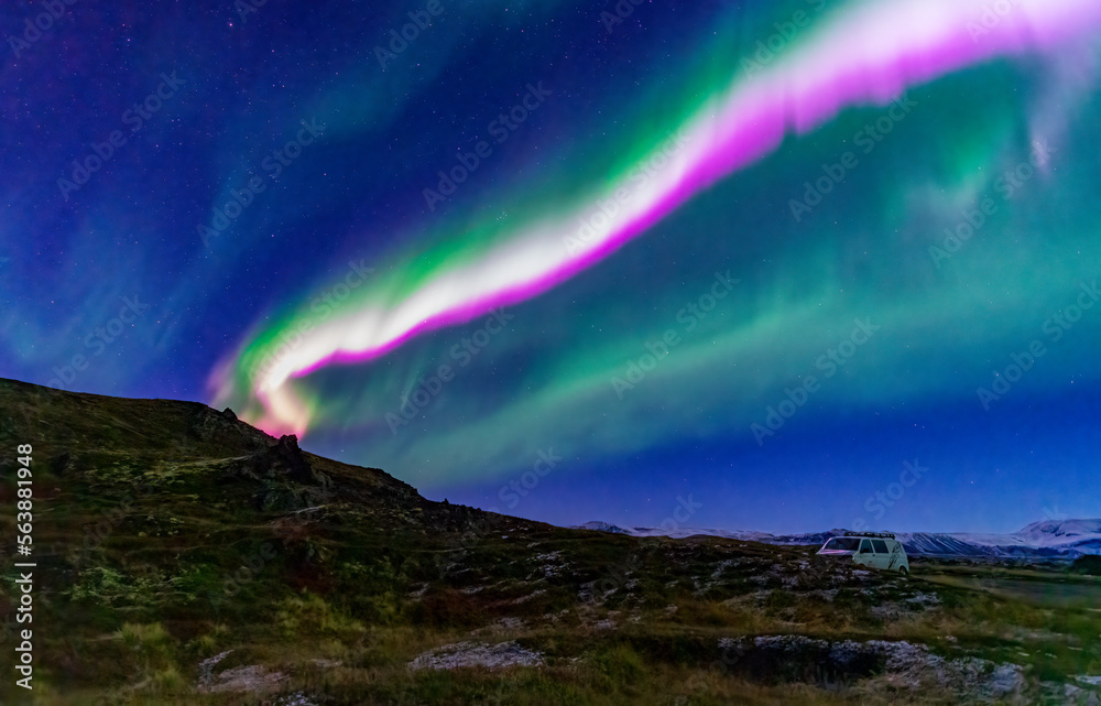 Green and purple northern light beams over the van