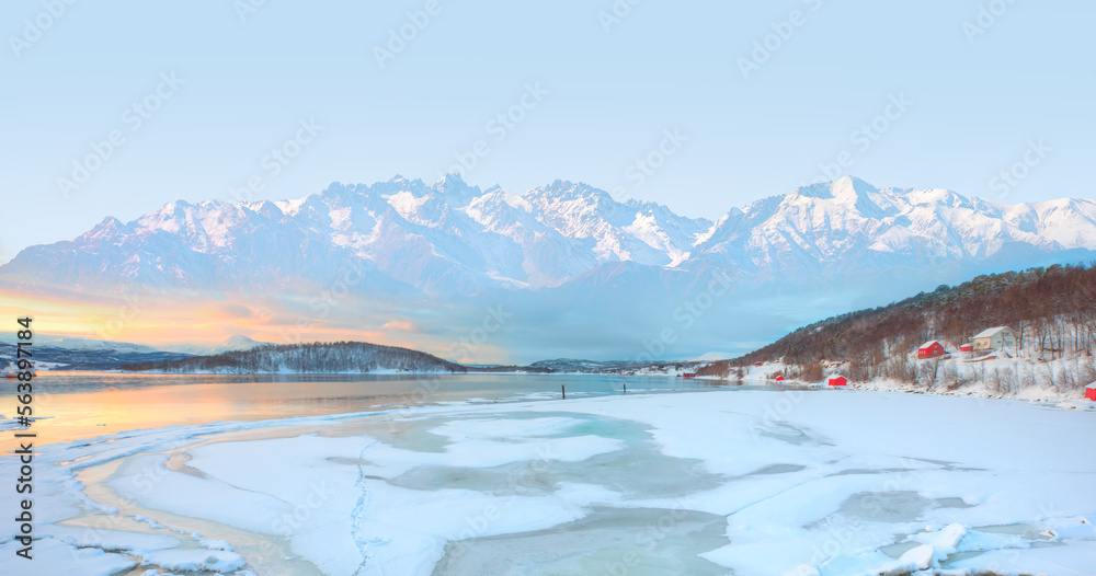 Beautiful winter lanscape with cracks on the surface of the turquoise (green) ice next to snowy moun