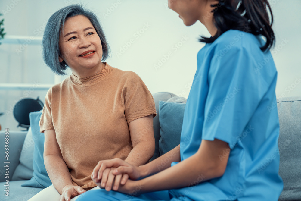 A contented senior woman visited by her personal caregiver and hold each others hands.