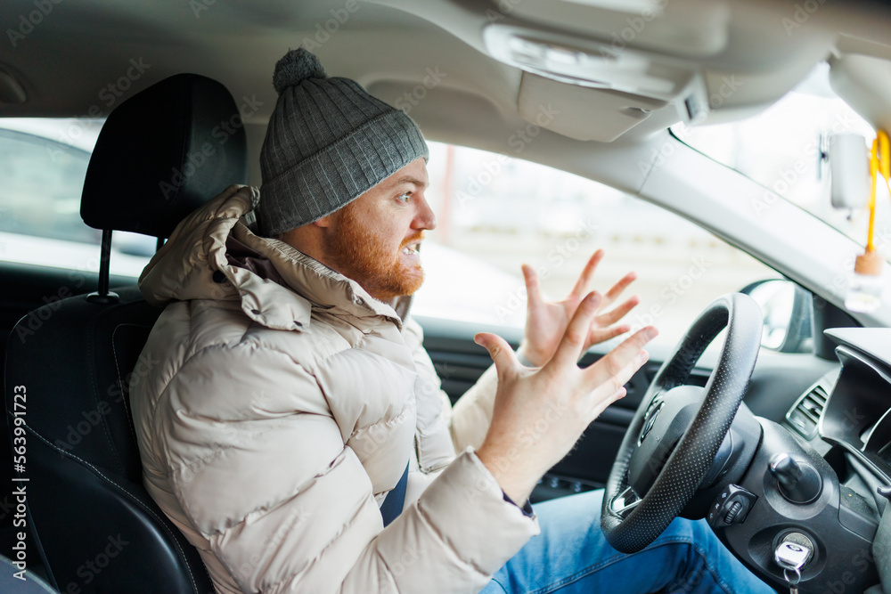 Angry driver in a traffic jam. He screams and gesticulates,