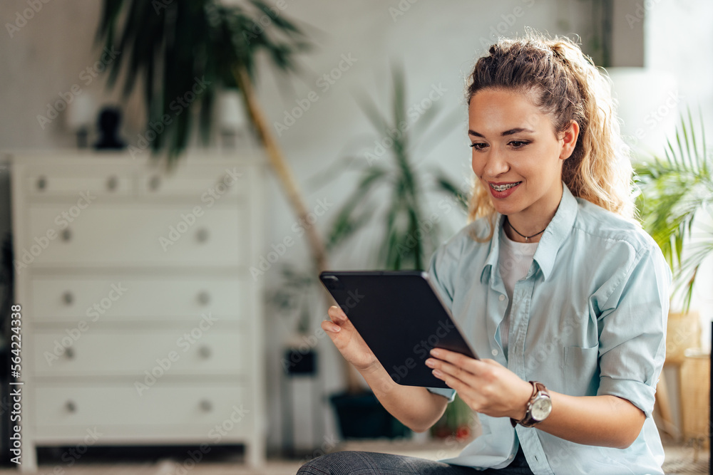 Smiling girl in a blue shirt, sitting at the office, using a modern technology.