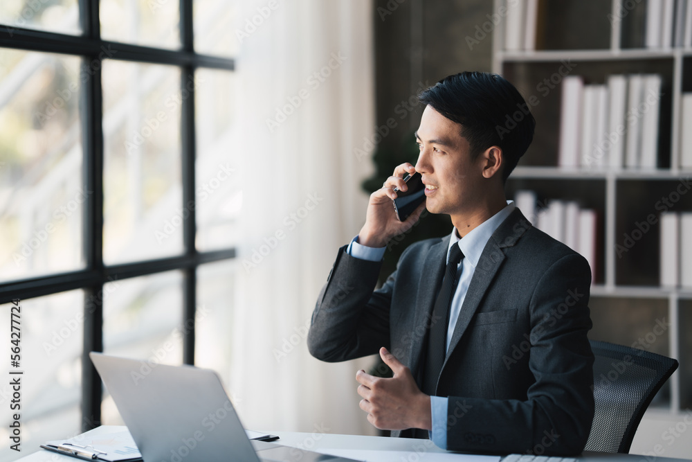 handsome businessman talking on cell phone while working on computer in office.