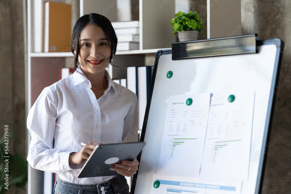 Asian businesswoman holding digital tablet in office room.