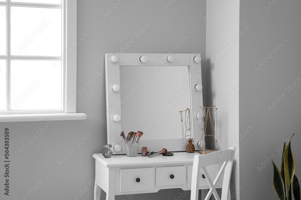 Table with cosmetics and mirror in light makeup room