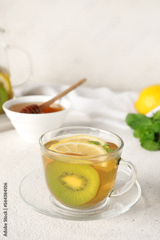 Glass cup of fruit tea with kiwi, mint and lemon on light background, closeup