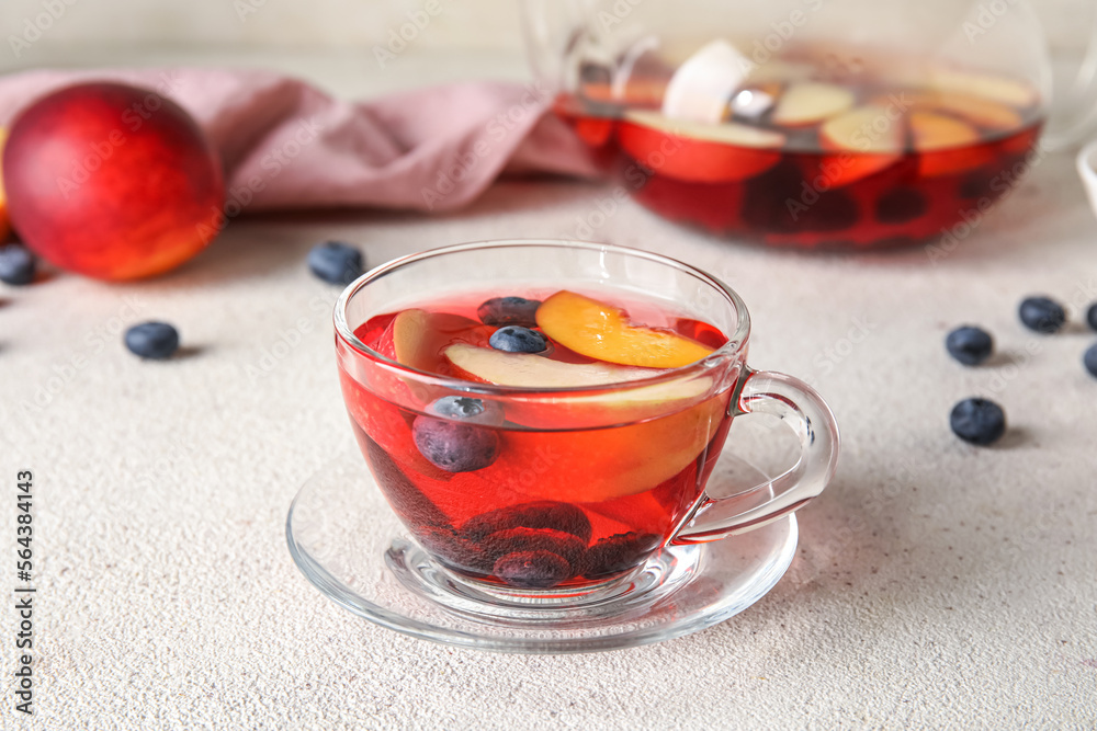 Glass cup of fruit tea with blueberries, apple and peach on light background, closeup