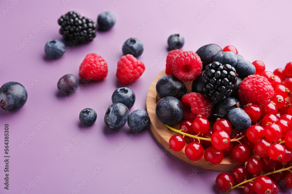 Wooden board with fresh ripe berries on color background