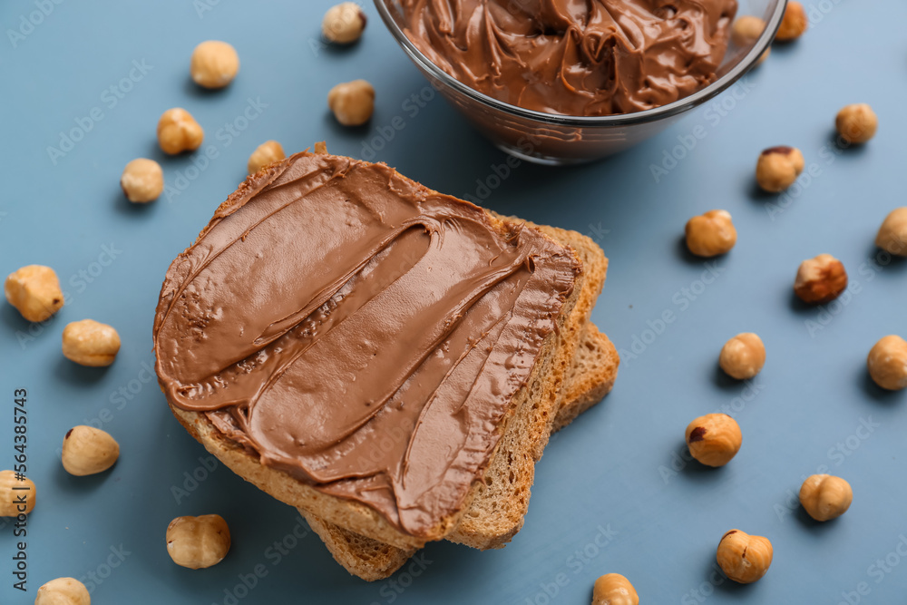 Tasty toasts with hazelnut butter and nuts on color background