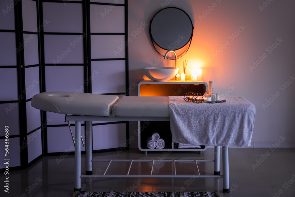 Interior of dark spa salon with couch, sink and folding screen