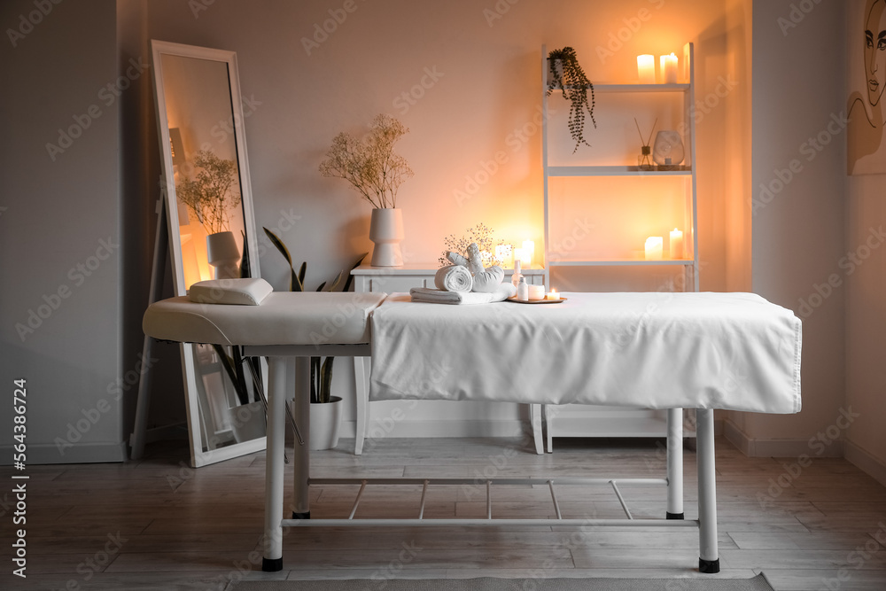 Interior of spa salon with couch, shelving unit and burning candles