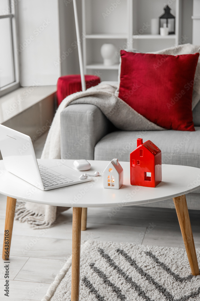 House candle holders, laptop and earphones on table in living room