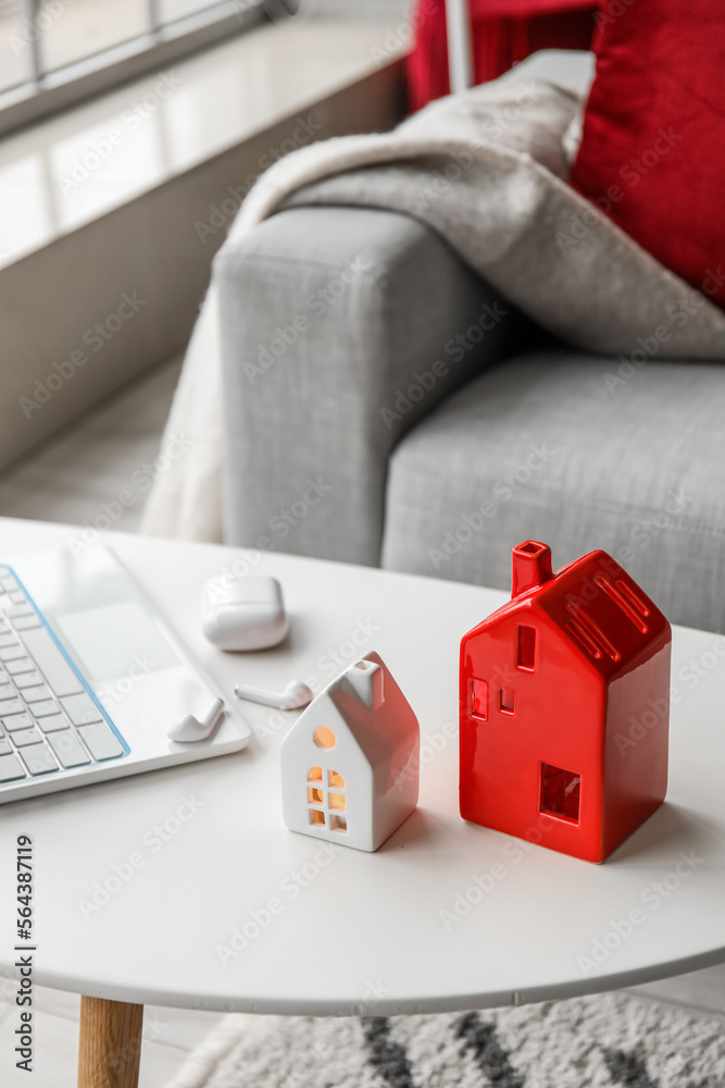 House candle holders, laptop and earphones on table in living room, closeup