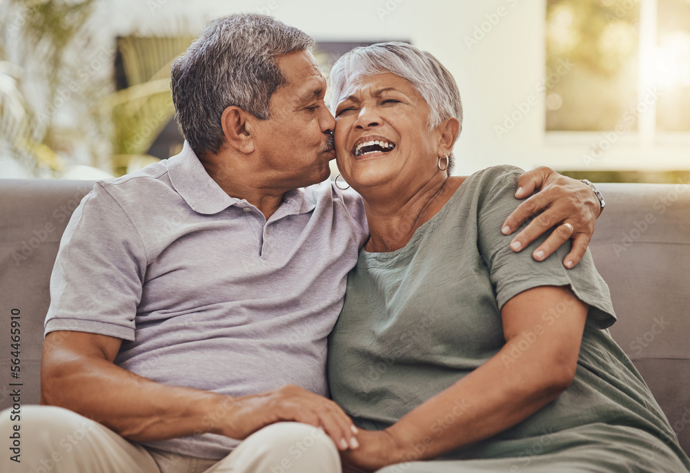 Happy, senior couple and kiss of elderly woman and man laughing with happiness on a sofa. Living roo