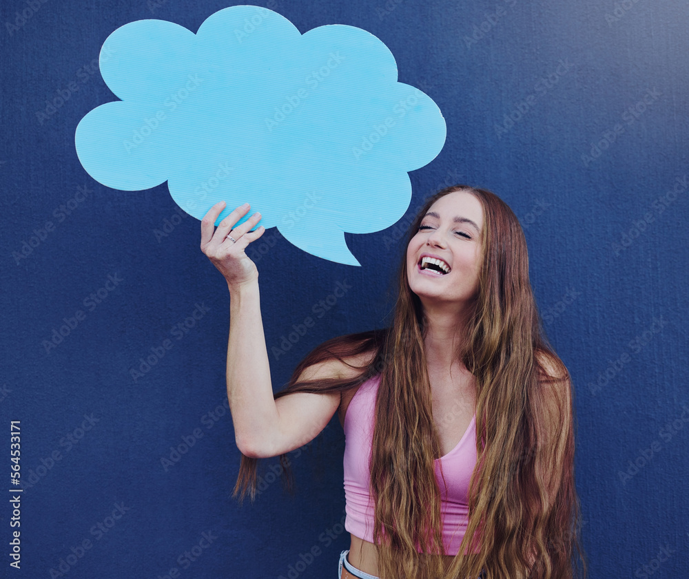 Happy woman holding a chat board with mockup space standing by a blue wall with a sign. Gen z, happi