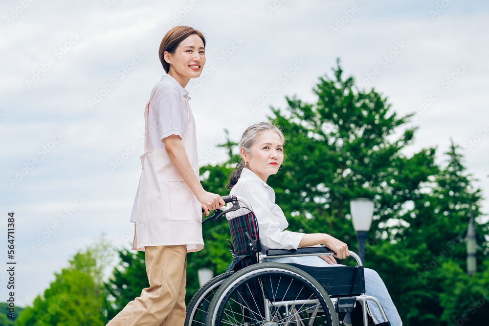 車椅子の女性と介護するエプロン姿の女性