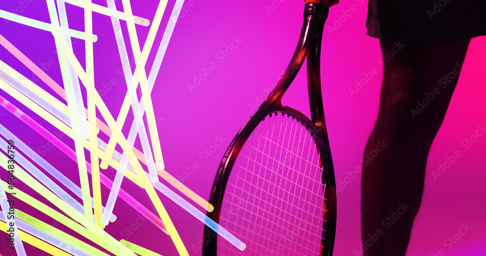 Midsection of african american male tennis player with racket by glowing lines on pink background