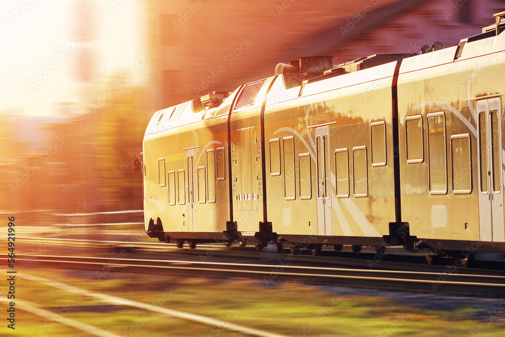 Passenger train moving along railway in sunset in summer.