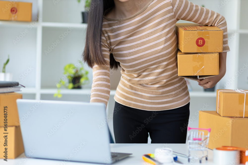 Woman starting a small business in a home office is working on a laptop to check orders from the int