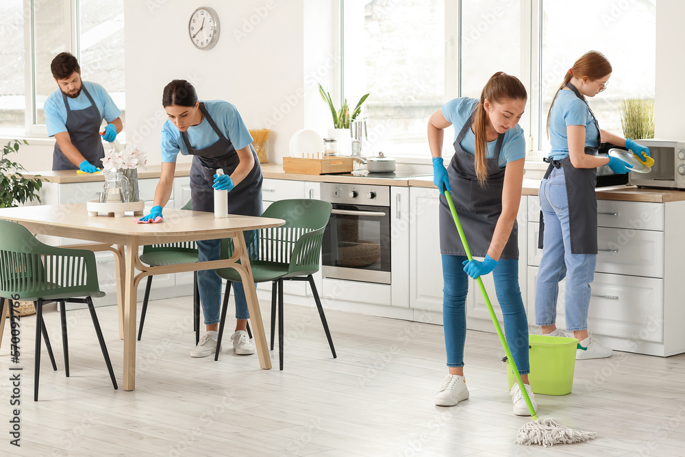 Young janitors cleaning in kitchen