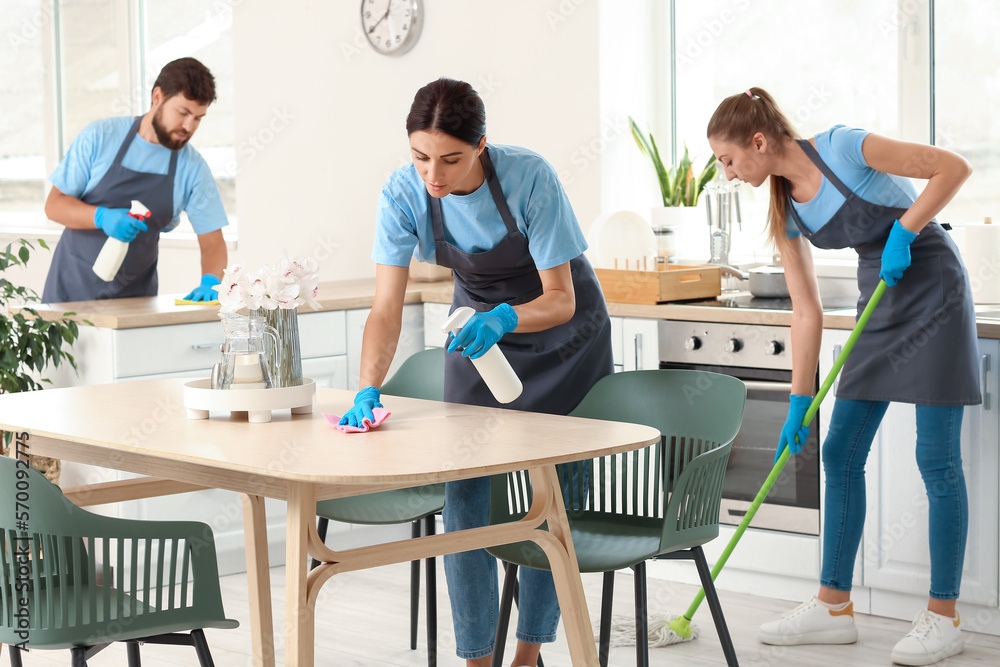 Young janitors cleaning in kitchen