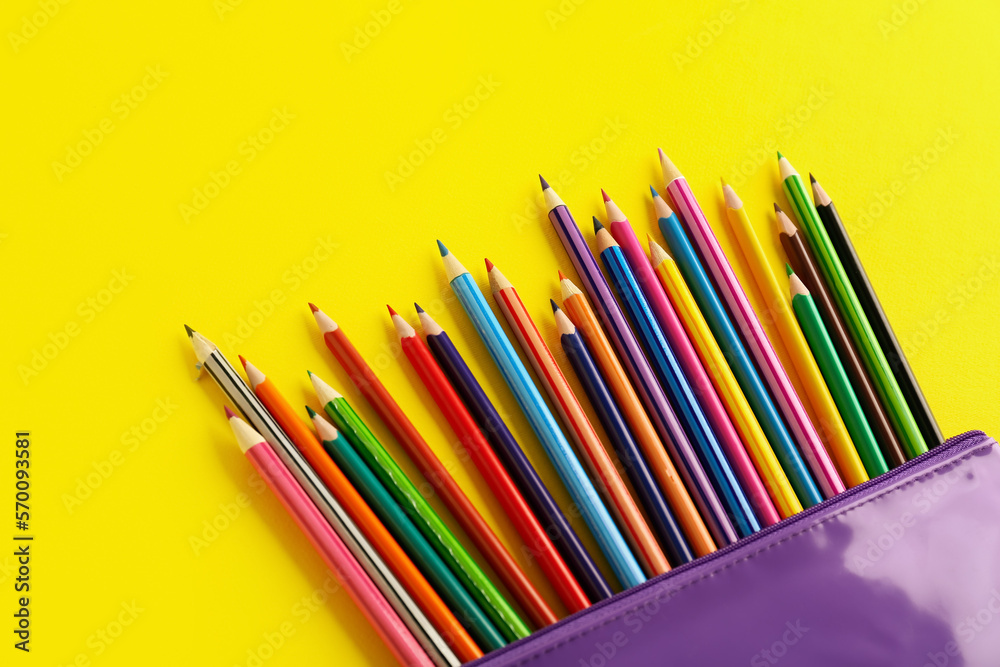 Case with colorful pencils on yellow background, closeup