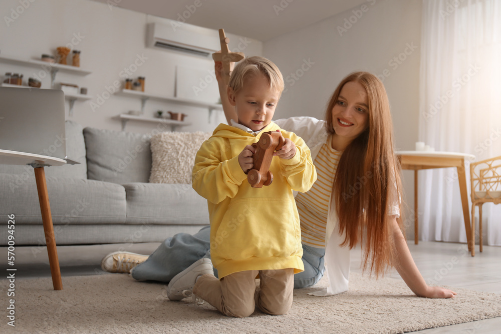 Mother and her little son playing with wooden toys at home