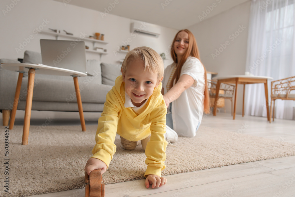 Little boy playing with toy car and his mother at home